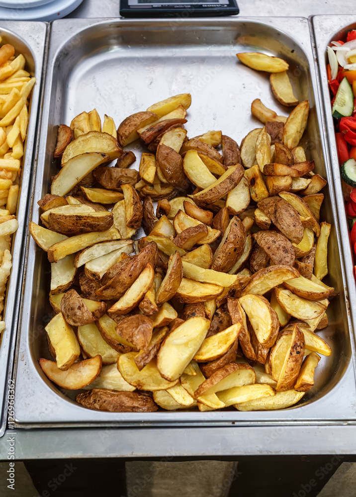 Steel container with roasted potato wedges, country stile potatoes Steel container with roasted potato wedges, country stile potatoes