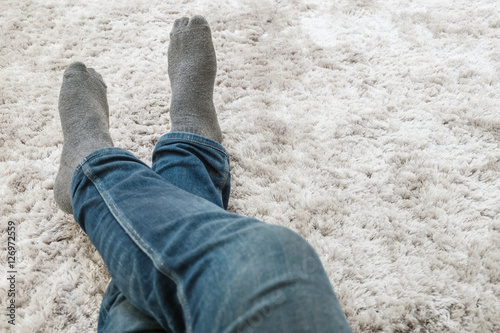 Closeup foot of man sit on gray carpet floor in house textured background with copy space