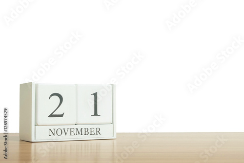 Closeup surface white wooden calendar with black 21 november word on blurred brown wood desk isolated on white background with copy space , selective focus at the calendar
