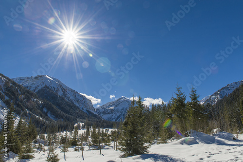 Blick auf verschneite Berglandschaft im Allgäu gegen die strahlende Nachmittagssonne. photo