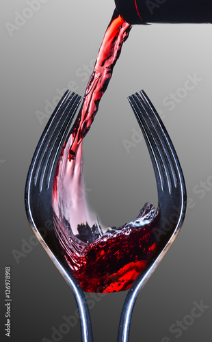 Wine and Dine. Two forks shaped like a wine glass with red wine being poured. Gray background. photo