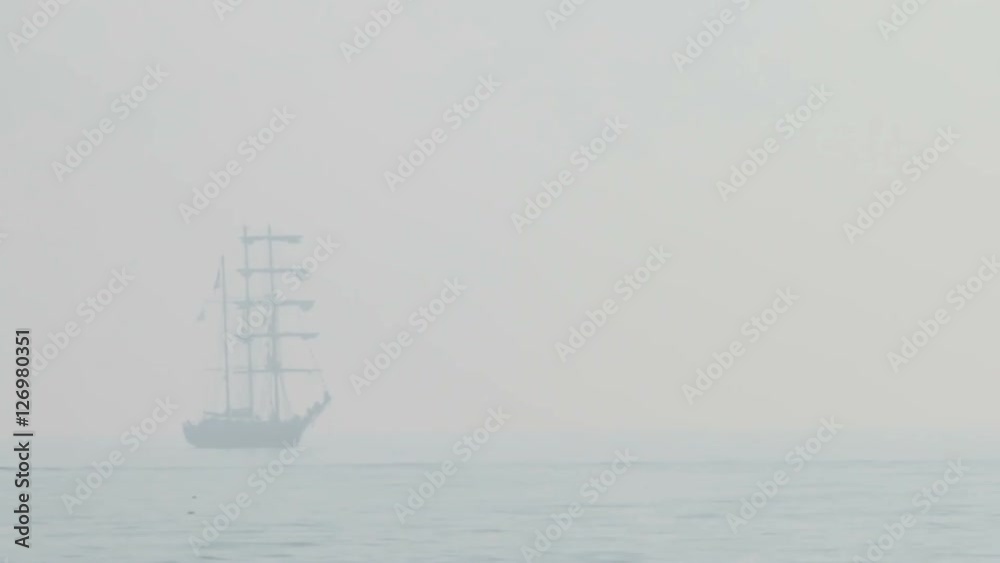 Tall ship sails on the open seas, misty foggy day