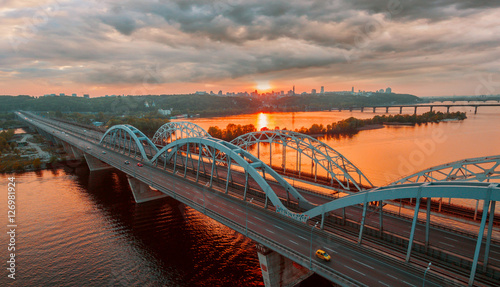Automobile and railroad bridge in Kiev, the capital of Ukraine. Bridge at sunset across the Dnieper River. Kiev bridge against the backdrop of a beautiful sunset in Kiev. Bridge in evening sunshine.