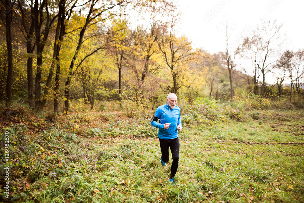 Senior man running in nature with smart phone and earphones. Senior man running in nature with smart phone and earphones.