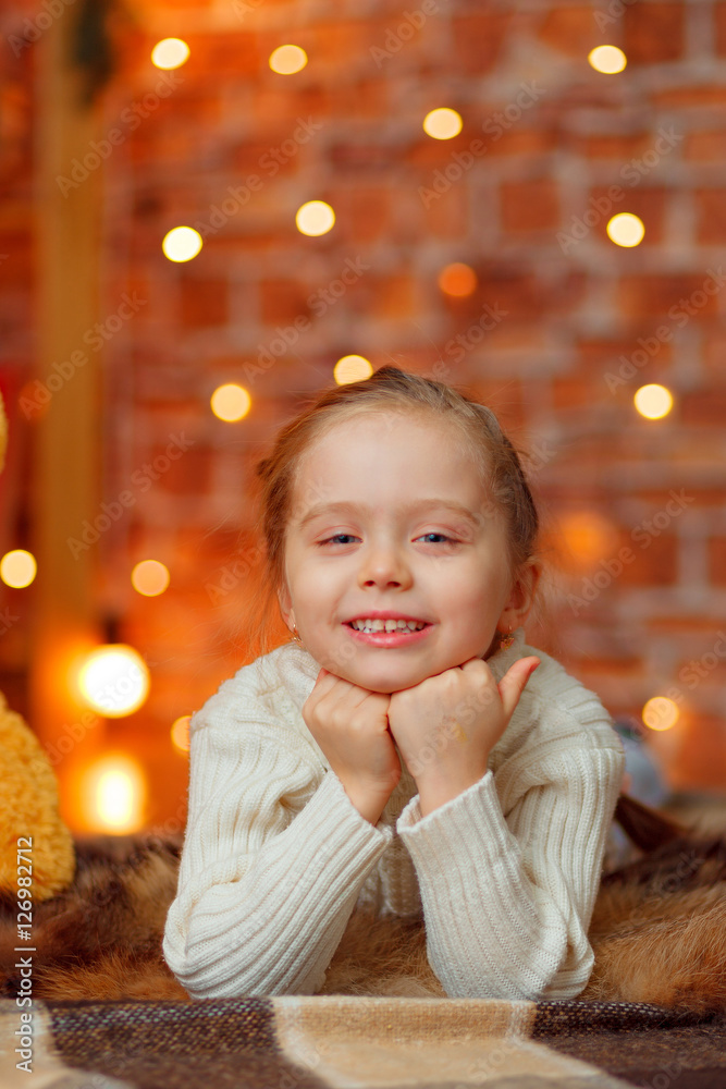 Little girl lying on the floor and looking into the camera. Christmas background Little girl lying on the floor and looking into the camera. Christmas background