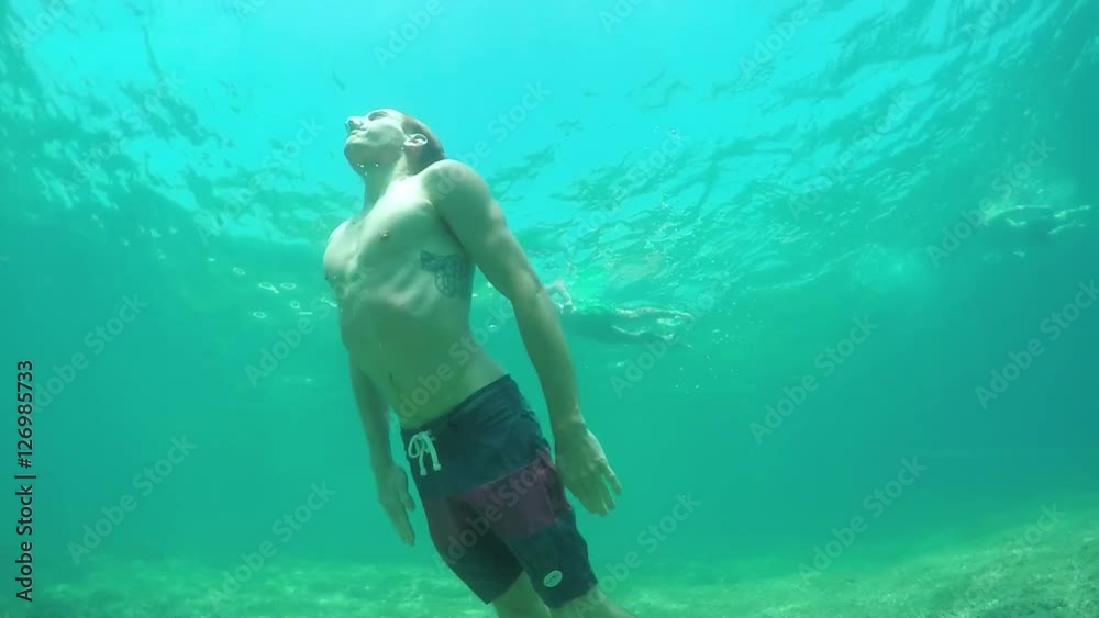 SLOW MOTION UNDERWATER: Man swimming in the ocean, coming to the surface for air SLOW MOTION UNDERWATER: Man swimming in the ocean, coming to the surface for air