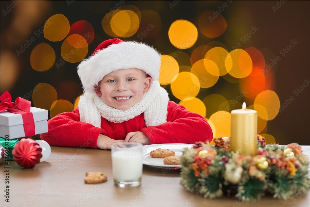 Portrait of happy boy in santa costume sitting at table Portrait of happy boy in santa costume sitting at table