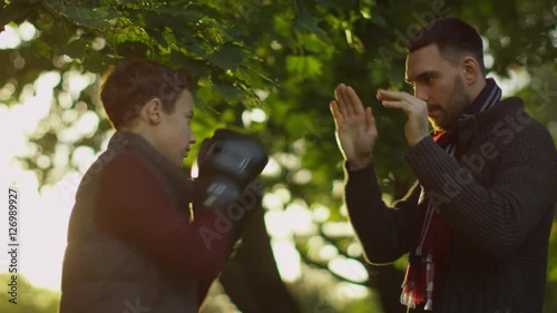 Father Teaches his Son Boxing with Gloves. Recreactional Activities in the Autumnt Park. Shot on RED Cinema Camera in 4K (UHD)  photo