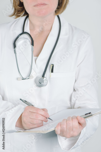 Female doctor writing on clipboard notepad blank paper
