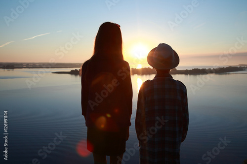 мальчик и девочка смотрят на восход солнца