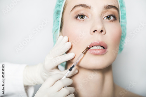 Doctor aesthetician makes lips correction and augmentation to female patient