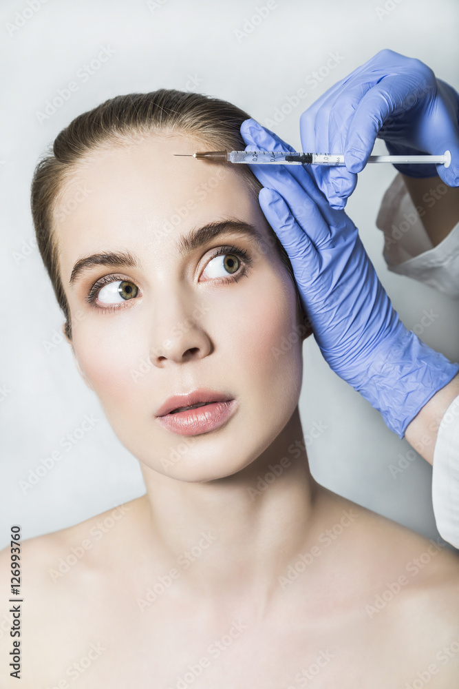 Doctor aesthetician makes face beauty injections to female patient