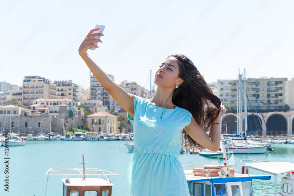 Lovely happy smiling tourist girl taking self-portrait using smartphone