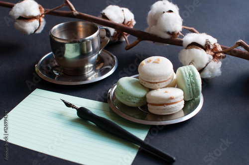 Coffee with notepad and French macarons on the dark background