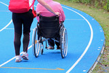 handicapped person on a wheelchair with an aide on the athletic