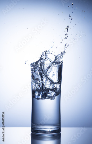 Falling ice cubes in a glass of water with splash