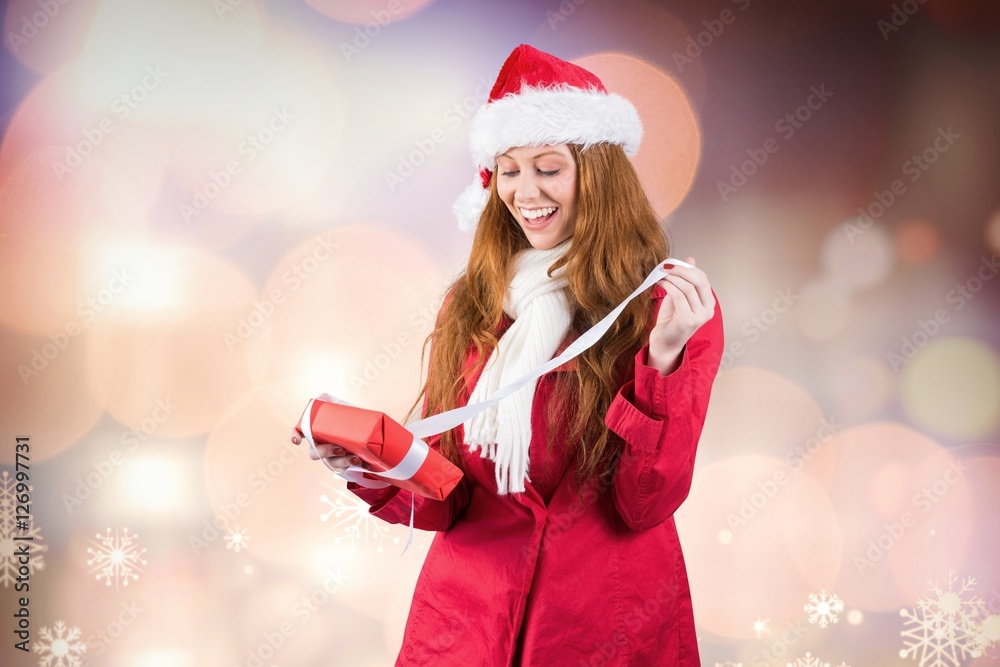 Excited beautiful woman in santa costume opening a gift