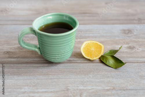 cup or mug of black tea with green leaves and lemon