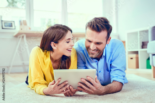 Cappy couple at home with tablet lying on the floor