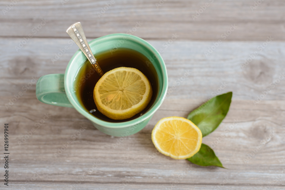 cup or mug of black tea with green leaves and lemon cup or mug of black tea with green leaves and lemon
