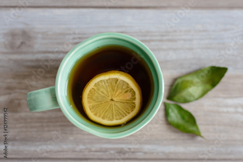 cup or mug of black tea with green leaves and lemon