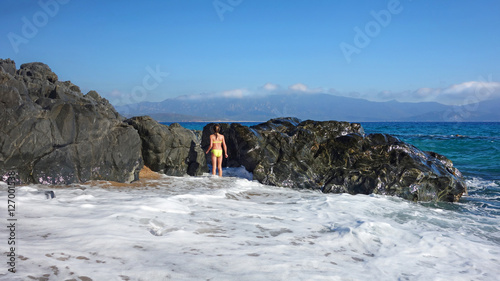 Enfant face à un rocher et à la mer photo