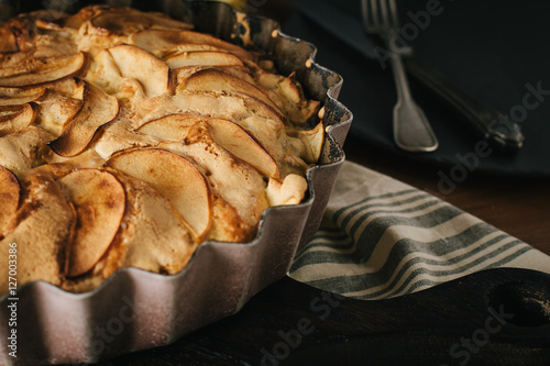 Homemade apple pie with nuts and cinnamon on dark background
