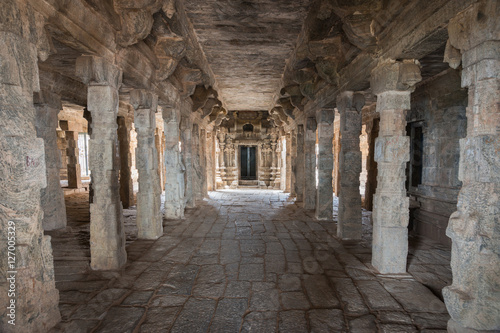 Dindigul, India - October 23, 2013: Inside the abandoned ruinous Shiva Temple on the Rock in Dindigul. Mandapam of stone pillars and ceiling leading to the inner sanctum. Beiges and Browns.