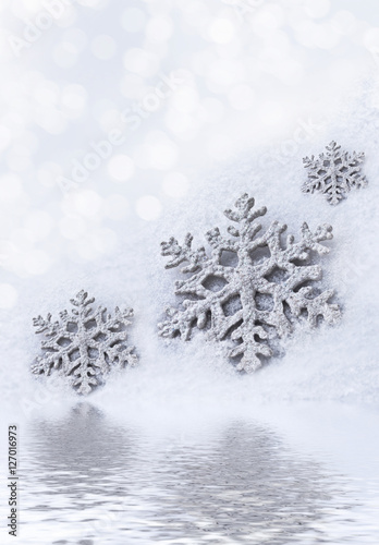 Glass toy snowflake on snow background.