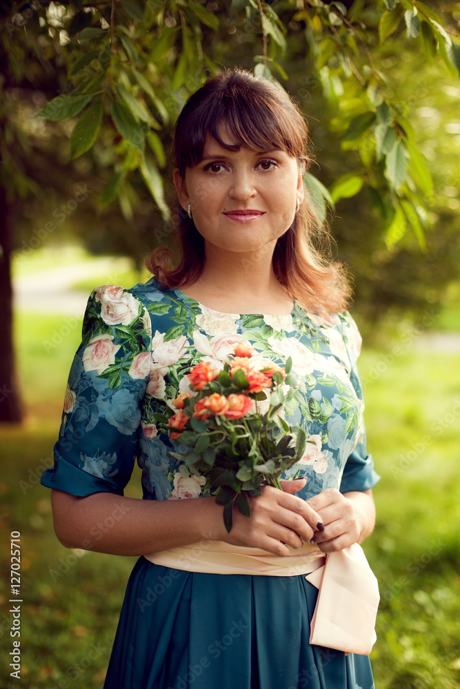 Young beautiful woman in floral dress posing in Park with a bouq Young beautiful woman in floral dress posing in Park with a bouq