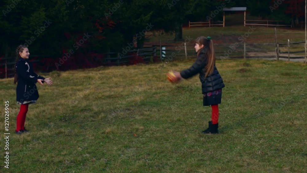 Two little beautiful girls playing with a ball on the nature Two little beautiful girls playing with a ball on the nature