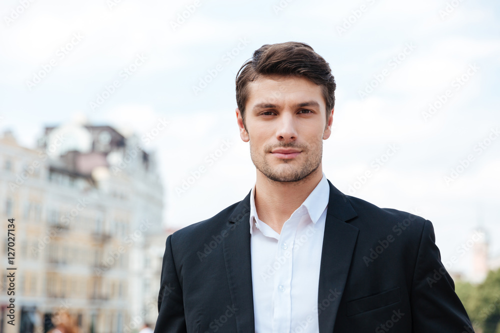 Handsome young businessman in suit standing outdoors Handsome young businessman in suit standing outdoors