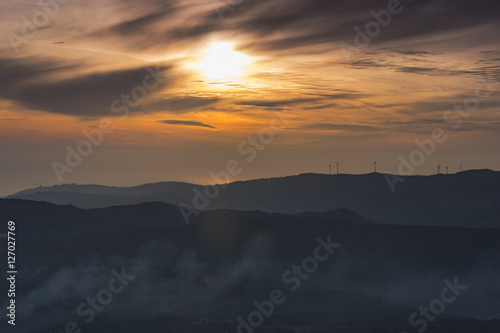 wind farm on the top of a mountain at sunset