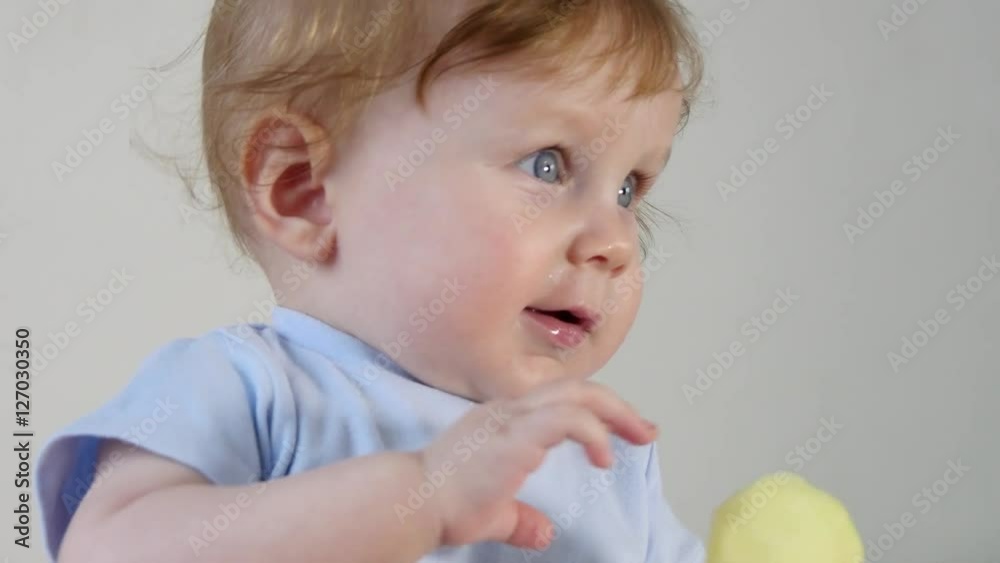 Baby boy holding and eating green apple Baby boy holding and eating green apple