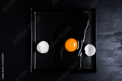 Egg and shell cracked on a black plate