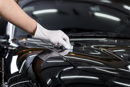 Car detailing series : Closeup of hand coating black car bonnet © bhakpong