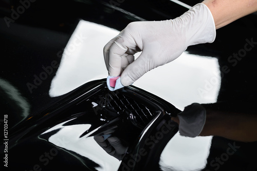 Car detailing series : Closeup of hand coating black car bonnet © bhakpong