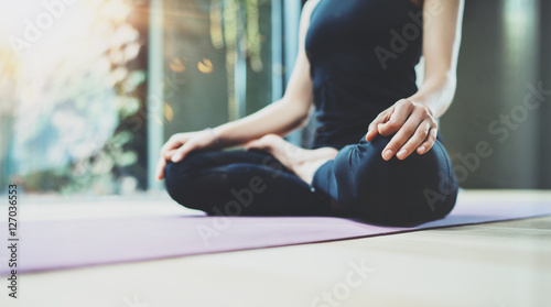 Close up view of happy young woman practicing yoga indoor. Beautiful girl practice lotus position in class.Calmness and relax, female happiness.Horizontal, blurred background, flares.