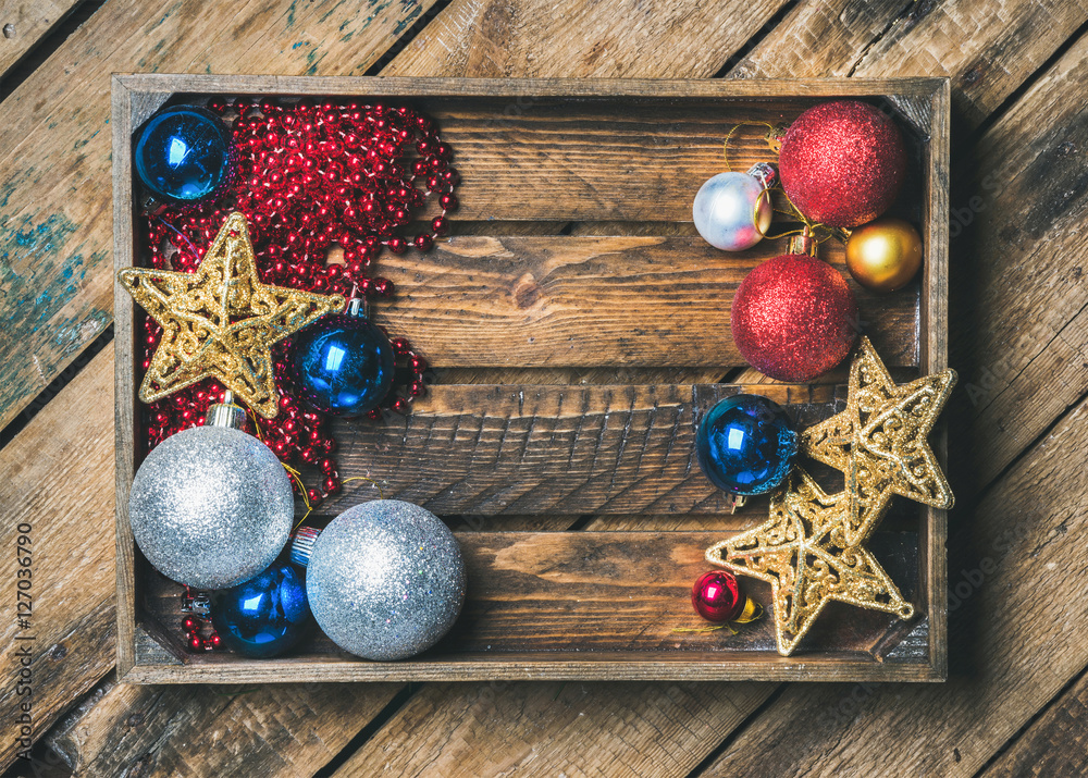 Christmas or New Year holiday decoration background. Christmas tree glittering toy stars, balls and garland in wooden box over rustic wooden background, top view, copy space, horizontal composition