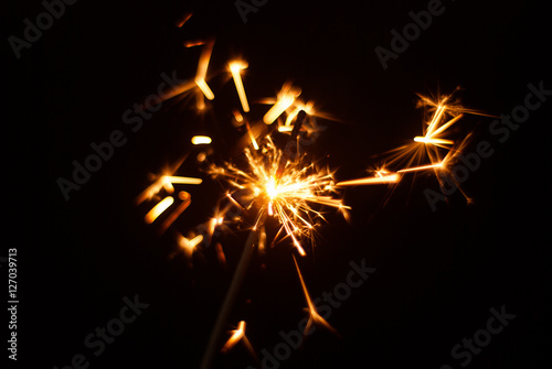 Sparkler on a black background, sparks fly in different directions,