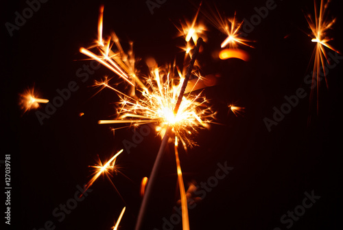 Sparkler on a black background, sparks fly in different directions,