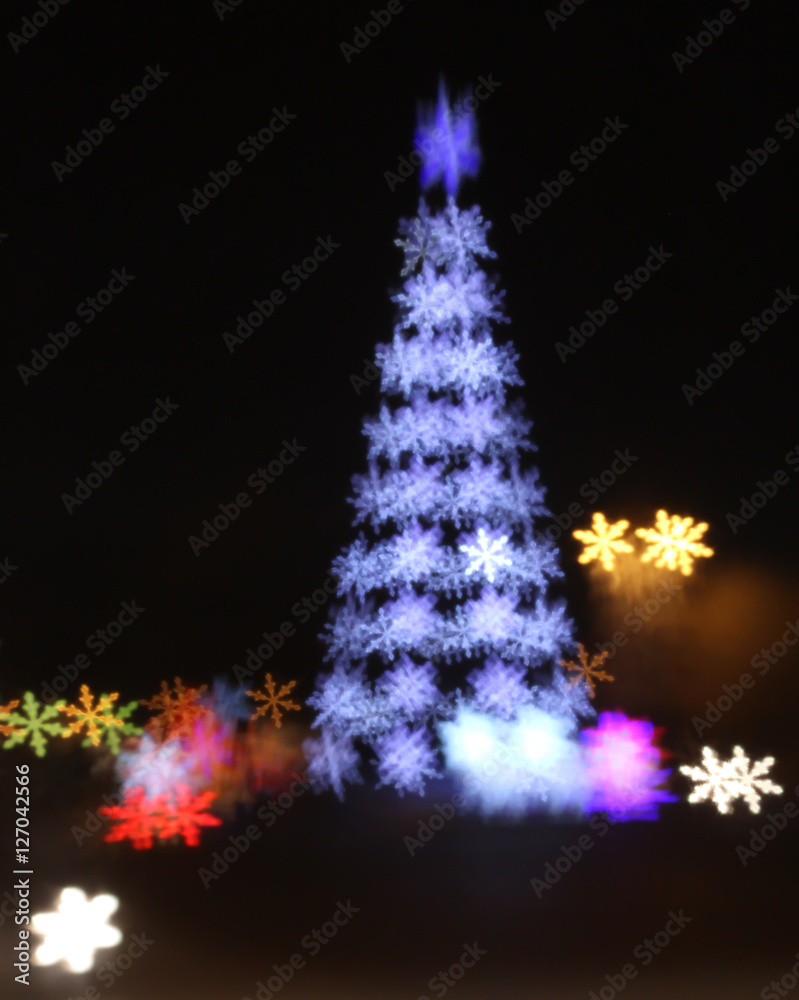 Abstract christmas tree background with defocused lights of snowflakes