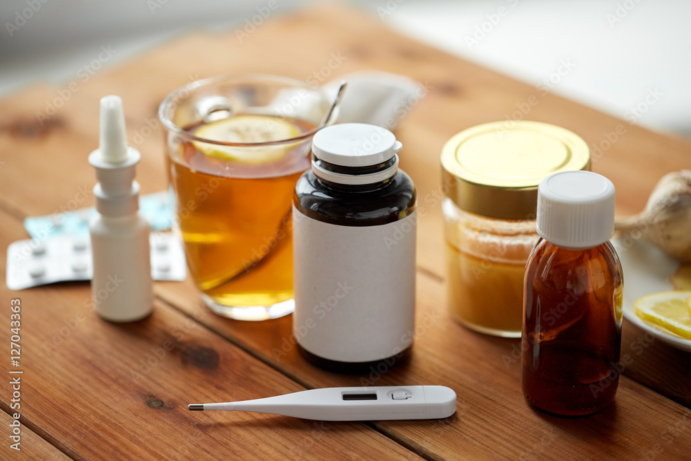 drugs, thermometer, honey and cup of tea on wood