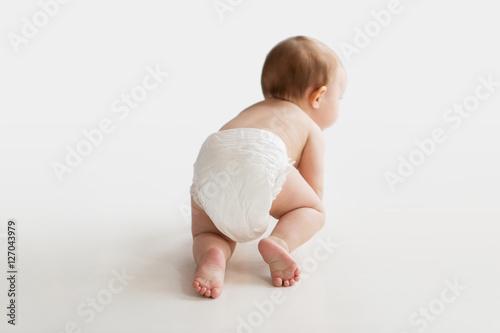 little baby in diaper crawling on white floor