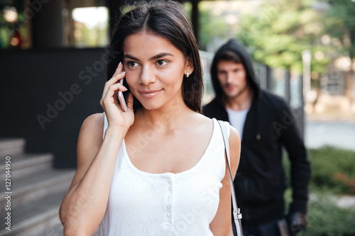 Woman talking on mobile phone and stalked by man criminal photo