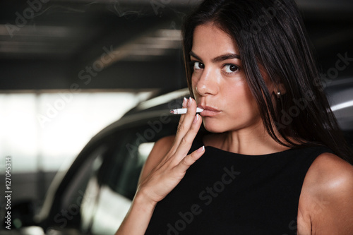 Woman smoking cigarette on car parking