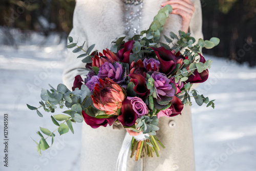 Wedding bouquet in hands of the bride. Winter time, snowy forest photo