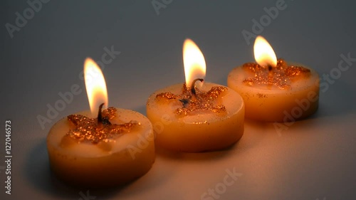 Three burning decorative candles with star pattern on a light background