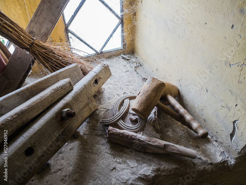 Picture of an old self-made wooden hammer mallet close up. Two wooden hammers laying on the yellow windowstool near the broom and wooden planks. A spider web in the coner of the window. photo