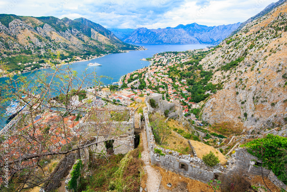 Panoramic view of old town, ruin of medieval  fortifications, stone walls of ancient fortress and mountain landscape in Bay of Kotor, Montenegro.